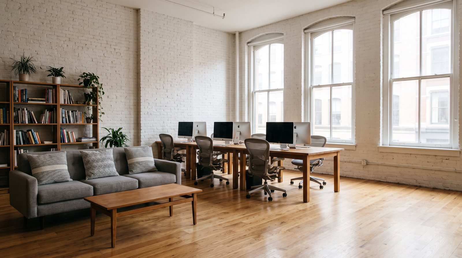 The same SoHo loft office reset on Monday morning, pillows back on the sofa, desks clear